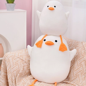 Set of two soft white plush ducks in large and small sizes on a cozy blanket