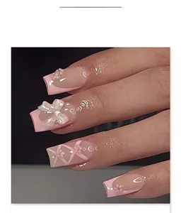 Detail of pink press-on nails with 3D white bows, flowers, and ribbon patterns