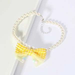 Detailed macro view of white pearl pet necklace with yellow plaid bow and metal clasp