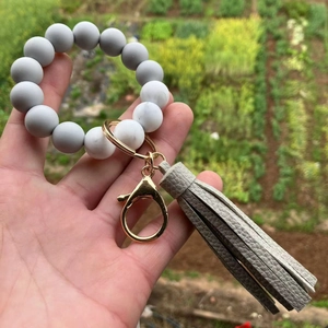 Detail of marble pattern silicone beads and gray tassel on a gold metal keychain ring