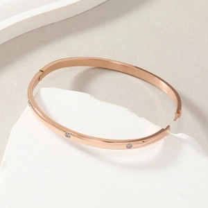 Polished rose gold stainless steel bangle featuring embedded crystals and clasp closure