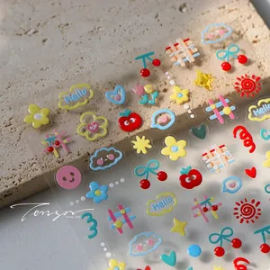 Vista macro di adesivi per unghie 3D con motivi floreali e ciliegie colorate