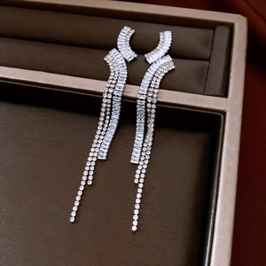 Macro shot of silver tassel earrings with geometric zircon inlay on a jewelry tray