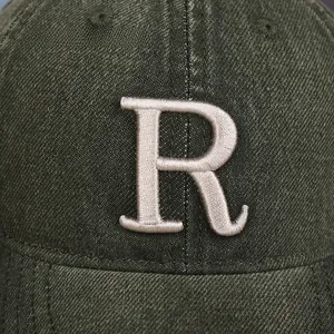 Gros plan sur tissu sergé vert foncé avec logo brodé en 3D lettre R blanche sur casquette