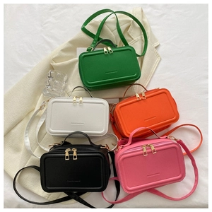 Flat lay of small suitcase style crossbody bags in five colors on a white blazer