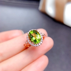 Detailed macro view of rose gold ring with oval green gemstone and halo diamonds