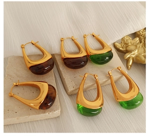 Detailed shot of retro gold drop earrings with amber and emerald resin inserts