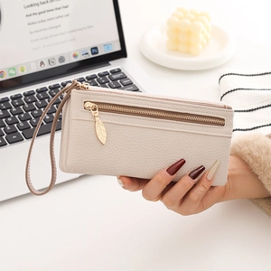 Detail of beige lychee leather long wallet with golden leaf zipper and wrist strap