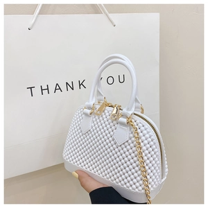 Detailed shot of white pearl textured shell bag with gold chain and top handles
