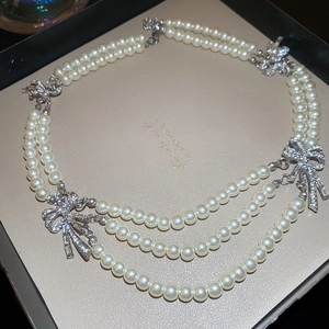 Detail of multi-layer pearl necklace with sparkling diamond-encrusted bow accents