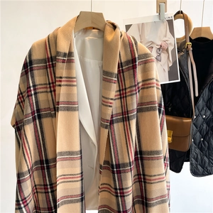 Dettaglio di una sciarpa a quadri beige simil cashmere abbinata a un blazer bianco chic