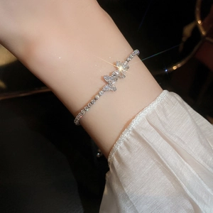 Detailed view of silver zircon butterfly bracelet worn on wrist with elegant white sleeve