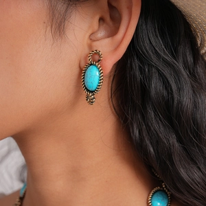 Close-up of bohemian style turquoise oval earrings with gold twisted metal borders