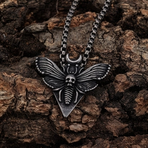 Gothic stainless steel death's-head hawkmoth pendant on rustic tree bark background