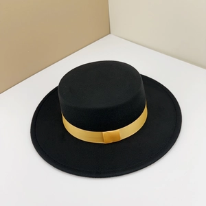 Close-up of elegant black flat top felt hat with a decorative shiny gold satin ribbon band