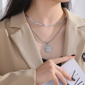 Detail of layered silver necklaces with a portrait pendant and flat snake chain