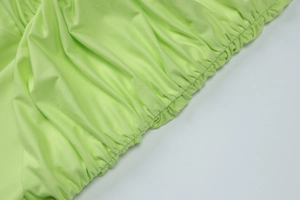Vue détaillée du tissu vert néon avec bords froncés et coutures élastiques