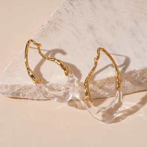 Artistic gold plated irregular resin teardrop earrings on a textured stone display