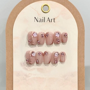 Handmade press-on nails in pink with star charms, diamond accents and rose gold patterns