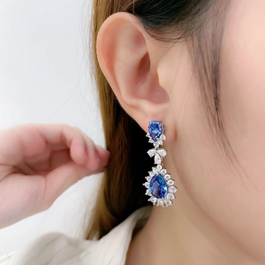 Close-up of luxury teardrop blue crystal earrings with white diamond pavé settings