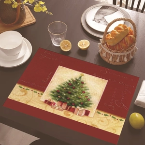 Close-up of a festive red Christmas placemat with gold trees on a wooden dining table
