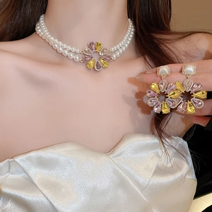 Detail von floralem Halsketten- und Ohrring-Set mit lila-gelben Steinen und Perlen