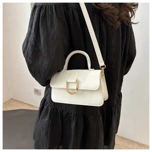 Detail of white mini crossbody bag featuring a signature D-shaped metal buckle and strap