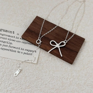 Minimalist 925 sterling silver bow pendant necklace on decorative card display