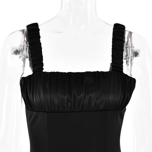 Detail of the pleated square neckline and satin fabric on the black mini dress