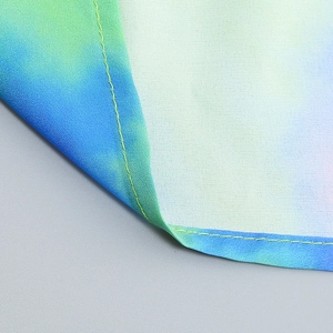 Macro shot of blue-green gradient fabric showing yellow reinforced stitching and texture