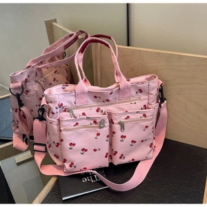 Detail view of pink canvas tote bag with cherry print showing side pockets in a mirror