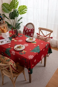 Detail of red Christmas tablecloth with snowflake and tree patterns on a wooden table