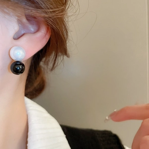 Minimalist black and white faux pearl geometric earrings worn by a female model