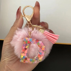 Detail of resin letter D keychain with colorful heart sequins, pink pompom and tassel
