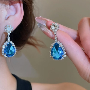 Close-up of luxury blue waterdrop earrings with crystals on a model for elegant look