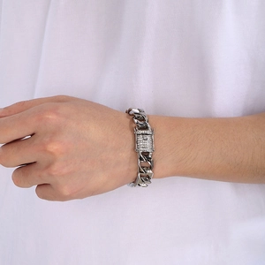 Close-up of men's silver Cuban link bracelet with iced-out rhinestone buckle on wrist