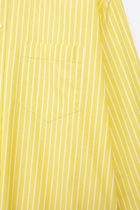 Detail view of a yellow striped cotton shirt featuring a functional chest pocket and stitching