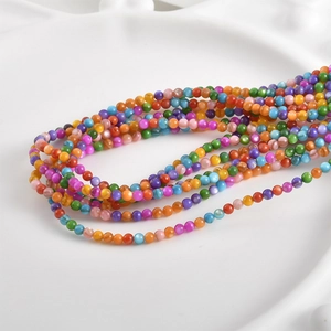 Macro shot of 3mm colorful natural freshwater shell round beads on a white textured plate
