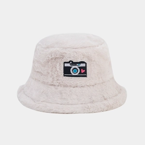 Close-up of fluffy beige faux rabbit fur bucket hat with retro camera and heart patch