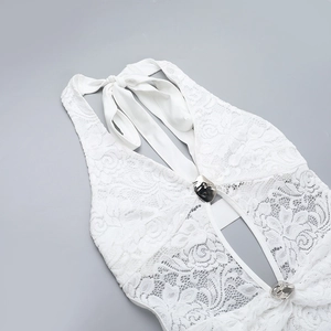 Détail de dentelle blanche ajourée avec liens en satin et ornements métalliques