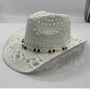 Detail of white woven cowboy hat featuring hollow patterns and shell bead decoration