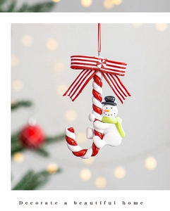 Close-up of a Christmas snowman and candy cane hanging ornament with a festive bow