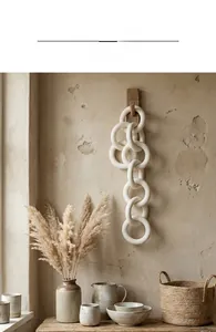 Minimalist white ceramic five-link chain wall decor hanging on a wooden hook in a cozy scene