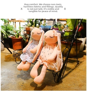 Detailed view of two plush rabbits in floral dresses sitting in a lush garden setting