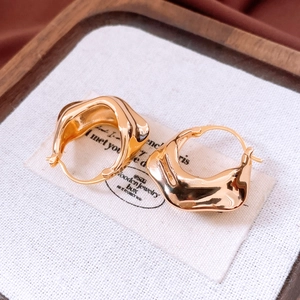 Detailed close-up of 18K gold plated earrings with irregular wrinkled texture on linen
