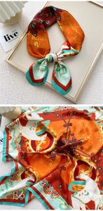 Close-up of square silk scarf with elegant deer and chain patterns in orange and green