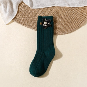 Detail of dark green ribbed knit socks with a black floral accent and pearl bead