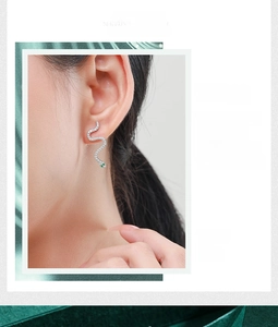 Detail of S925 sterling silver snake stud earrings with white zircons and green gem eyes