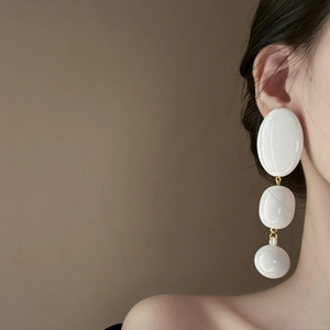 Chic white acrylic oval drop earrings with golden metal links worn by a female model