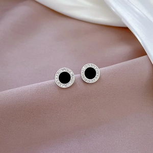 Macro view of silver titanium steel earrings with black inlay and white zircon stones